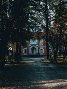 Elegant historic mansion surrounded by lush trees in a park setting in Podgorica, Montenegro.