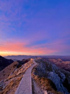 Beautiful sunset view from Lovćen Mountain, Montenegro, featuring a scenic walkway and stunning landscape.