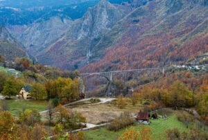 Scenic autumn landscape featuring Durdevica Tara Bridge amidst mountainous terrain in Montenegro.